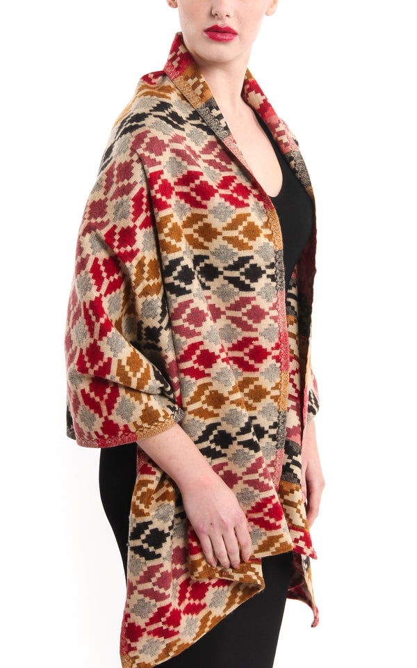 Geometric snowflake pattern tibet shawl with red beige back accents draped around shoulder